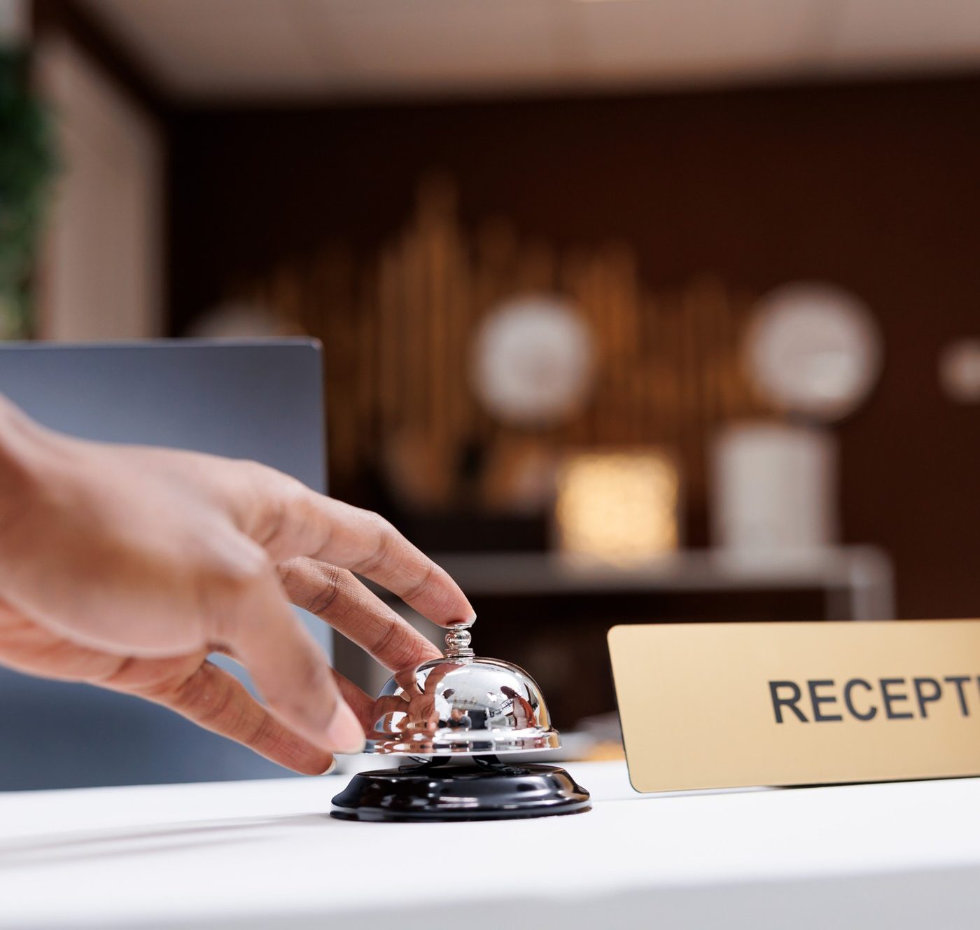 Mano pulsando la campanilla de recepción de un hotel