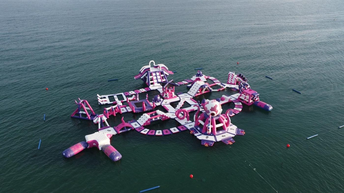 Vista aérea de un parque acuático flotante rosa y blanco